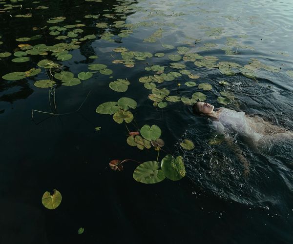 Person meditating in a serene natural environment by a lake.